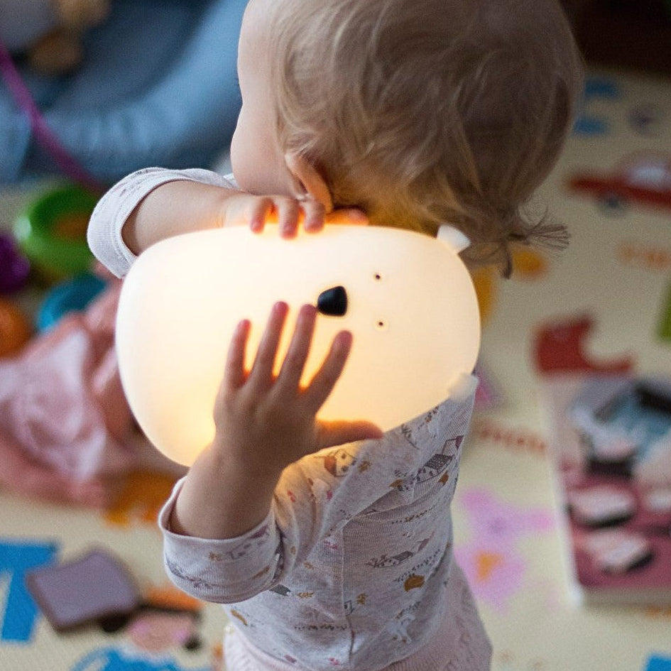 Child holding a glowing bear night lamp